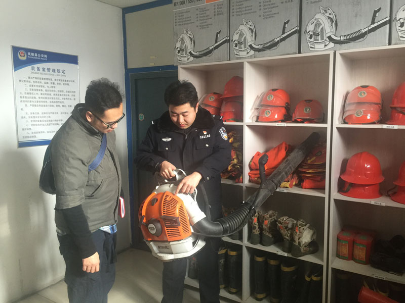 民警王雍賀向記者（左）講解新進(jìn)的輕便型德國(guó)進(jìn)口風(fēng)力滅火器的使用