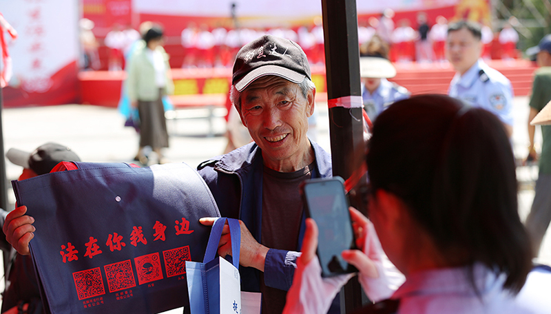 頭題圖，法治文藝節(jié)目展演活動(dòng)現(xiàn)場(chǎng)，司法局工作人員發(fā)放原創(chuàng)普法購(gòu)物袋。